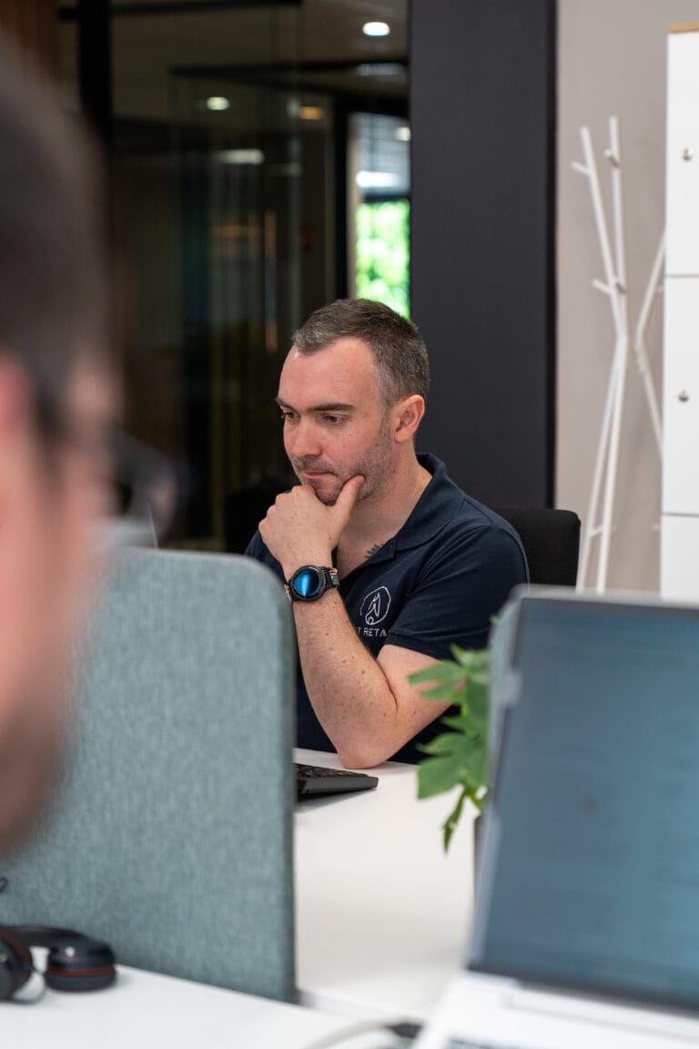 Thomas en train de réfléchir devant son ordinateur en open space