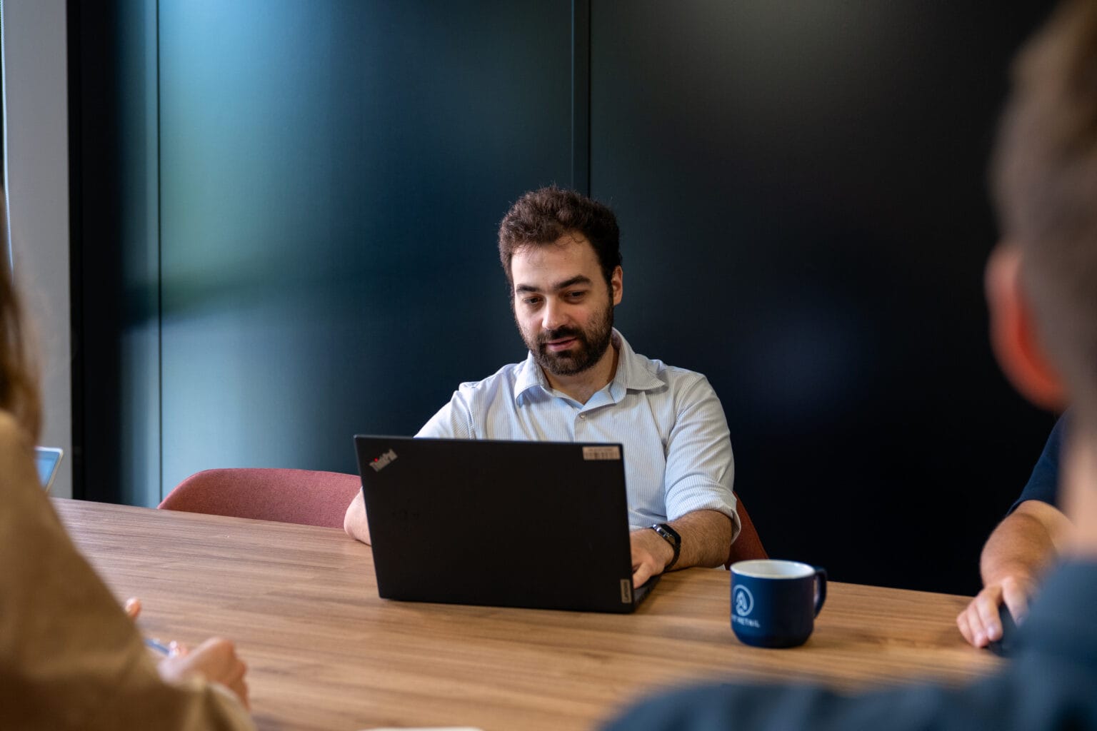 Collaborateur Fit Retail concentré sur son ordinateur portable en salle de réunion