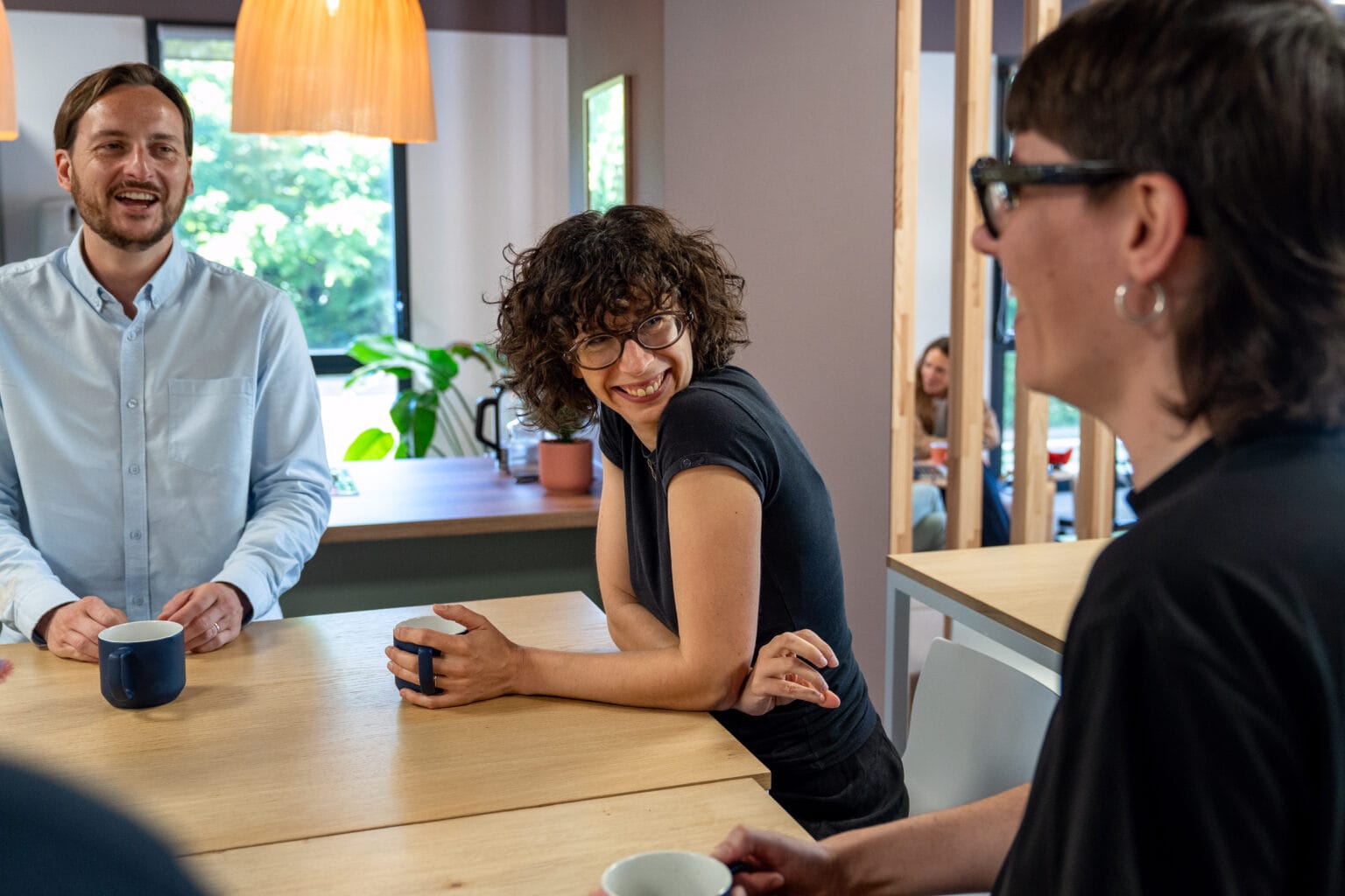 Collaboratrice Fit Retail aux cheveux bouclés en train de boire un café avec ses collègues
