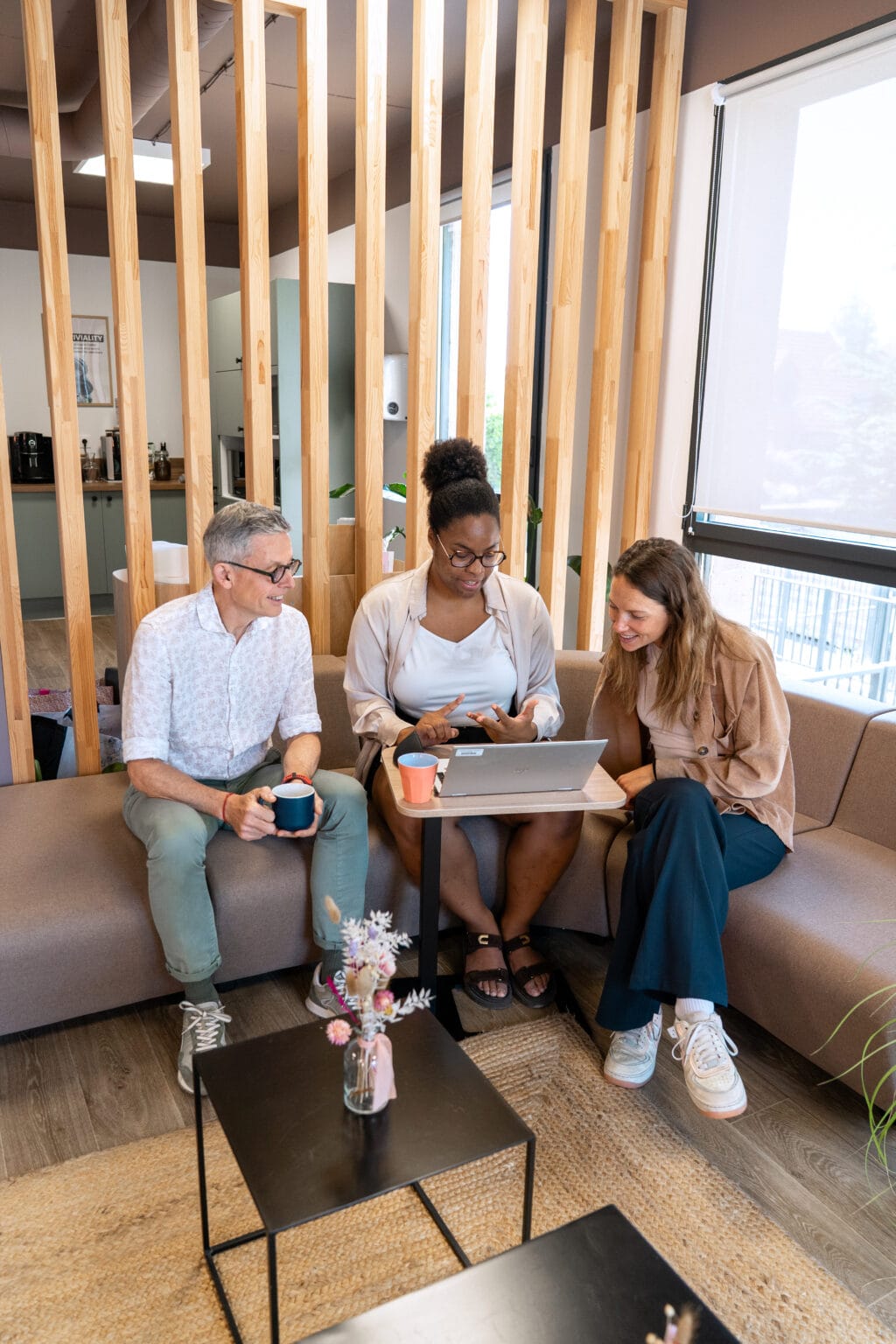 Collègues Fit Retail travaillant ensemble sur un canapé avec ordinateurs portables