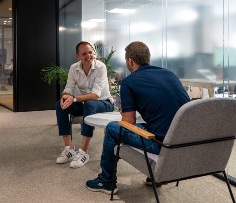 Deux collègues Fit Retail en discussion détendue dans un espace confortable du bureau