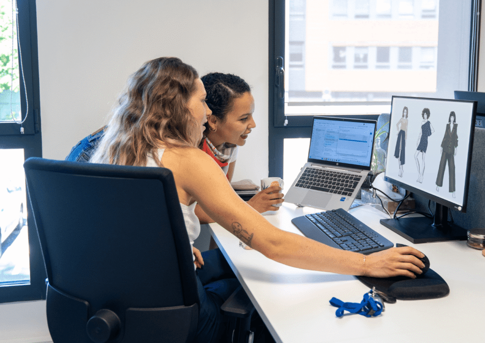 Deux collaboratrices Fit Retail échangent devant leurs ordinateurs portables au bureau